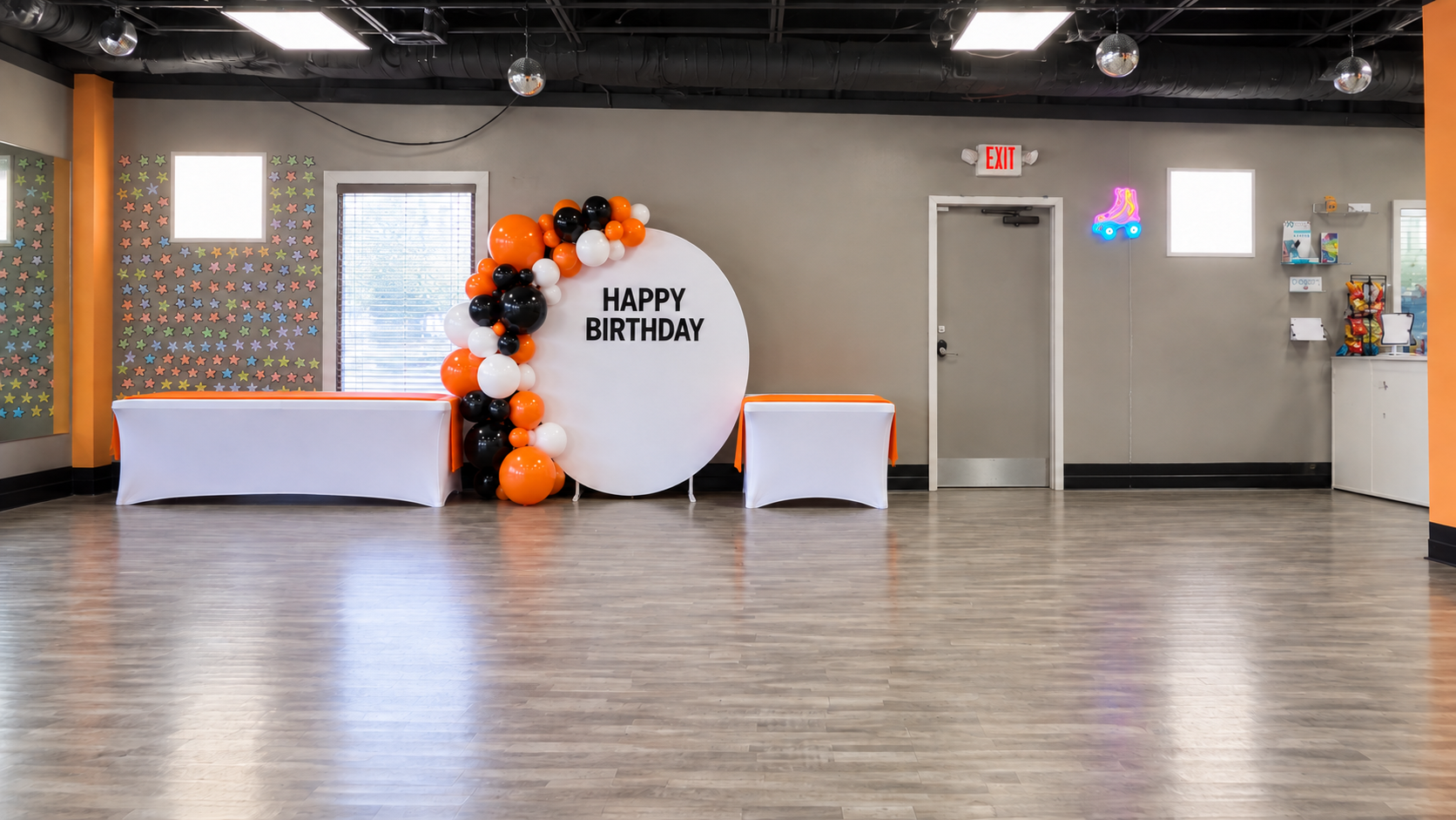 Private Atlanta event studio with black, white and orange balloons, a white backdrop and decorated display tables.